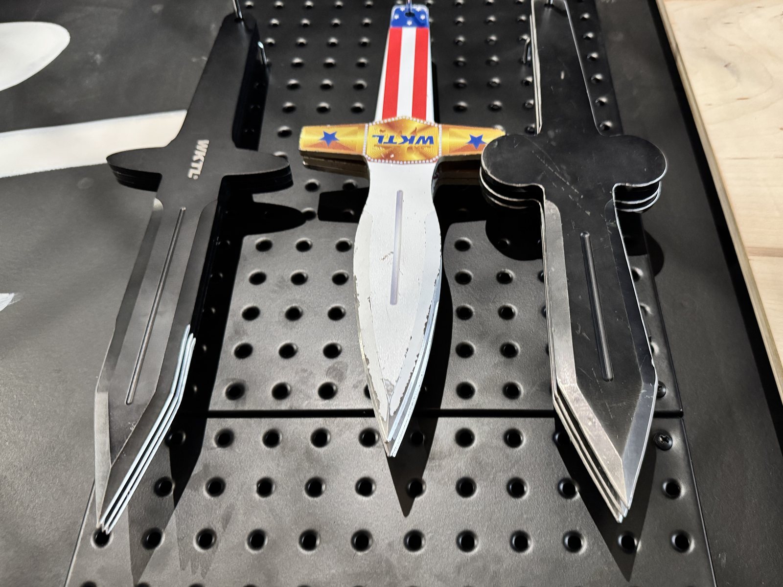 Throwing knives, big axes and ninja stars laid out on the Pacific Axes board
